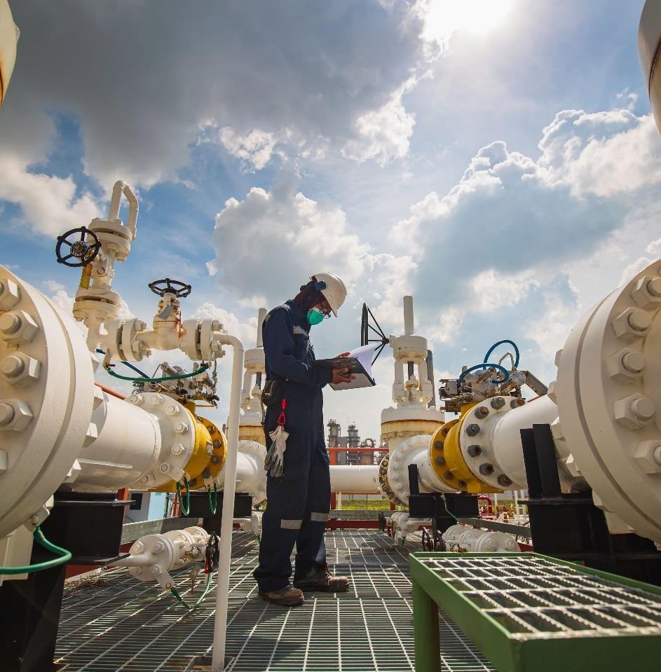 An oilfield professional inspecting industrial pipework